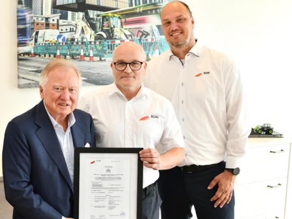 Lord Bamford recebe a certificação oficial dos funcionários da RDW, André van de Visser e Marc Feijen, permitindo a venda de motores de combustão a hidrogênio na Holanda.